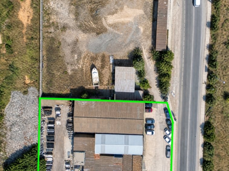 Vista aérea de nave industrial y solar con zona de aparcamiento en La Unión, Murcia — suelo libre junto a construcción existente.