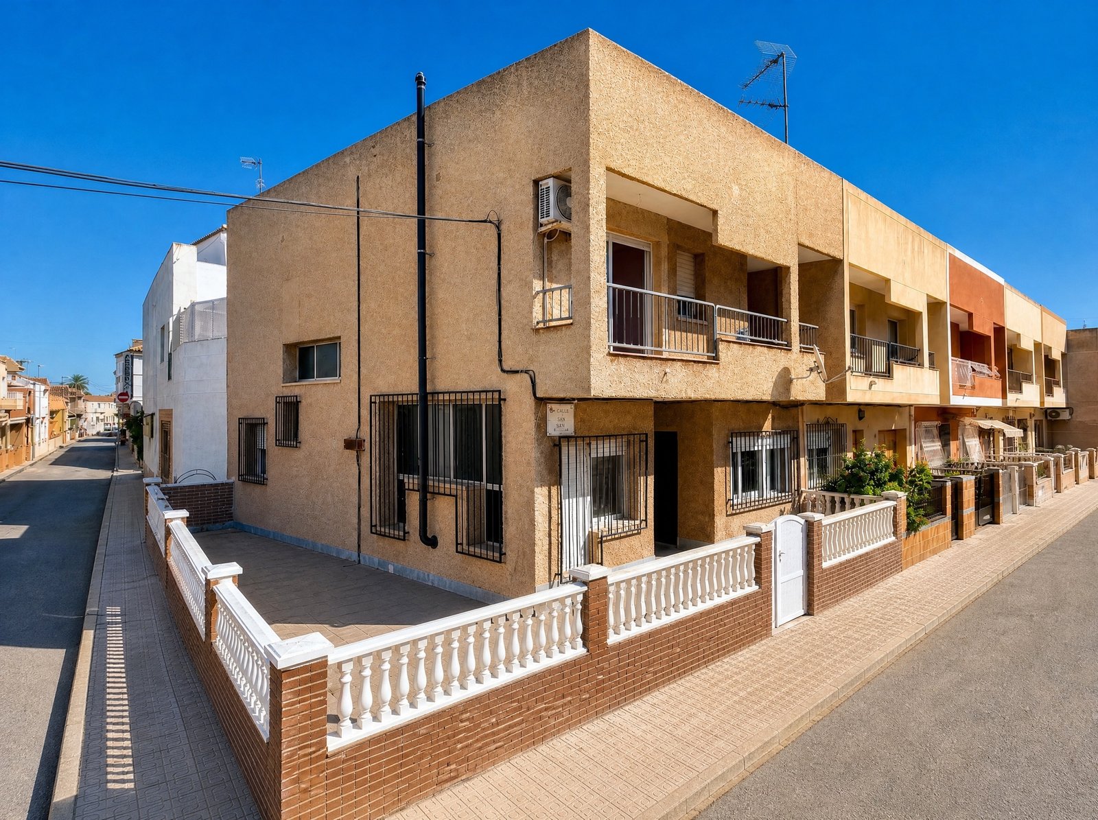 Fachada de vivienda adosada de dos plantas con terraza y balcón, en calle residencial tranquila de la Región de Murcia, Costa Cálida — Red Nest Properties